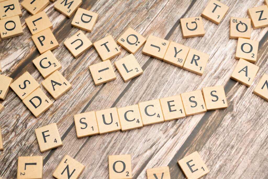 Close-up of wooden letter tiles spelling 'success' on rustic surface, symbolizing achievement and goals.