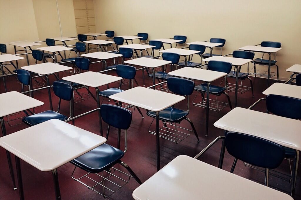 An indoor view of a modern, clean classroom with rows of empty desks and chairs.