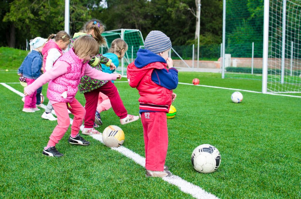 Kids having fun playing soccer outdoors on a sunny day in a park.