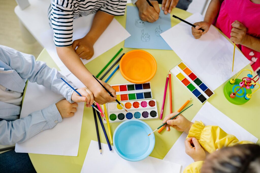 Kids enjoying watercolor painting indoors, fostering creativity and learning.